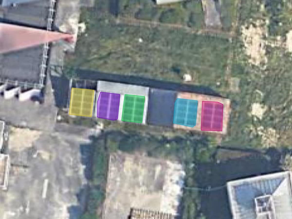 Vista aérea del tejado de un edificio agrícola, con cinco grupos de paneles solares delineados cada uno con su propio color