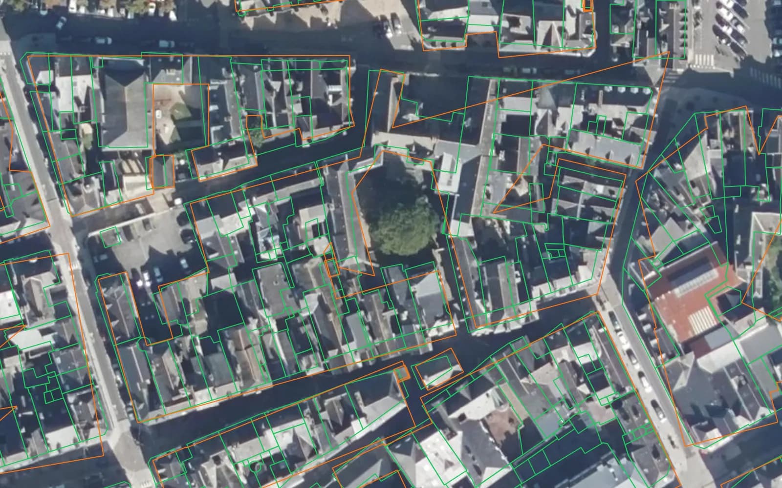 Aerial photo of Vitré's old town with slate roofs. Thin green outlines, BD TOPO, divide each terraced block into dozens of individual houses; orange outlines, Microsoft, wrap each whole block in one shape, with a few stray triangles across courtyards.