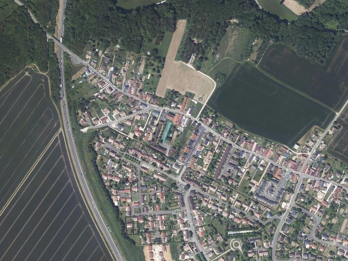 The edge of a village in Eure-et-Loir on the IGN orthophoto: ploughed fields, a hedge and a wood as the only edges, and the housing estate that stops at the last parcel.