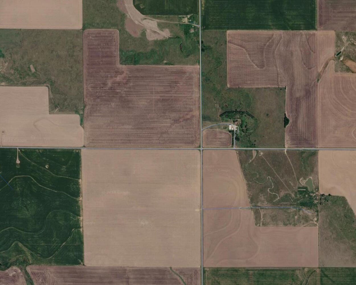 Satellite imagery of a rural district with OSM highway lines in blue over it. Two main roads carry lines, while a dozen visible dirt tracks between fields carry nothing.