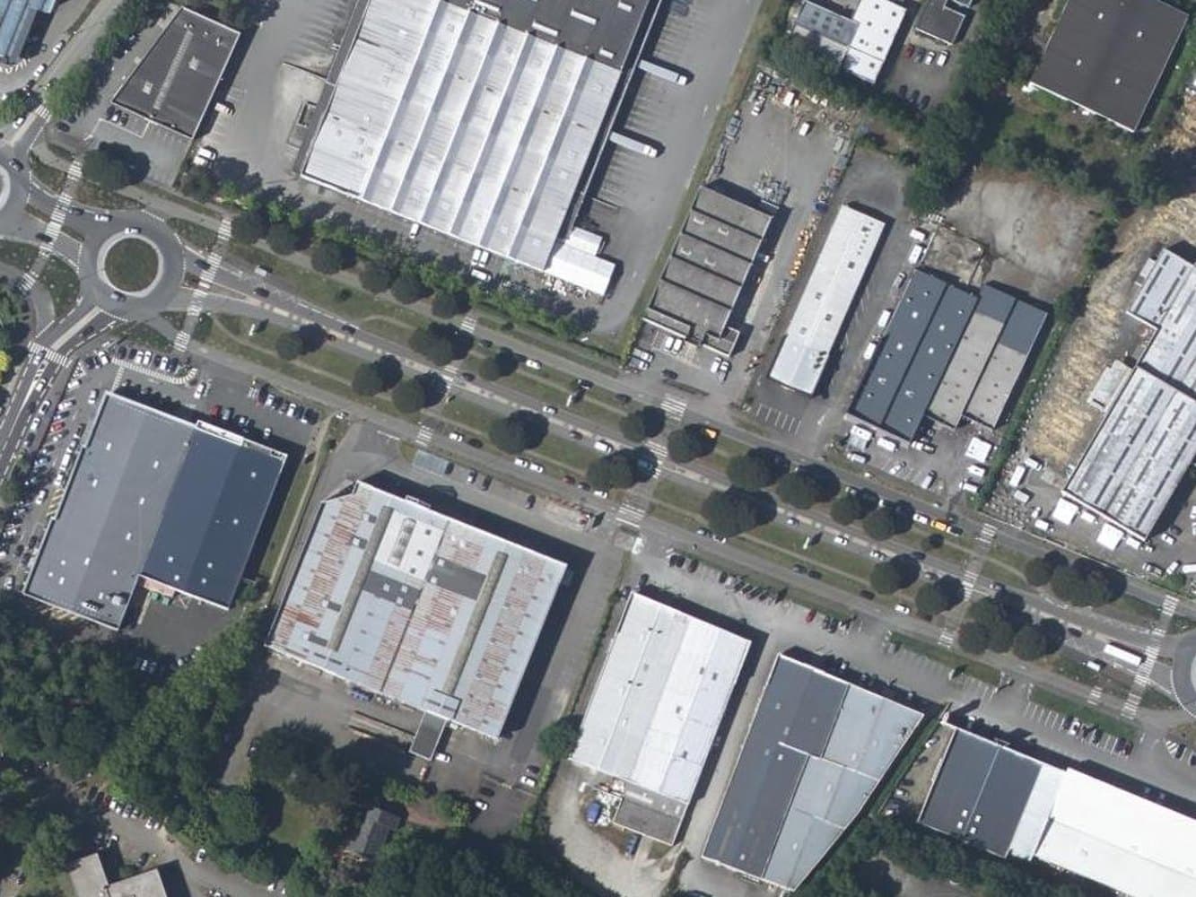 Aerial view of a commercial strip road with two carriageways, retail warehouses, twin roundabouts and very large car parks.