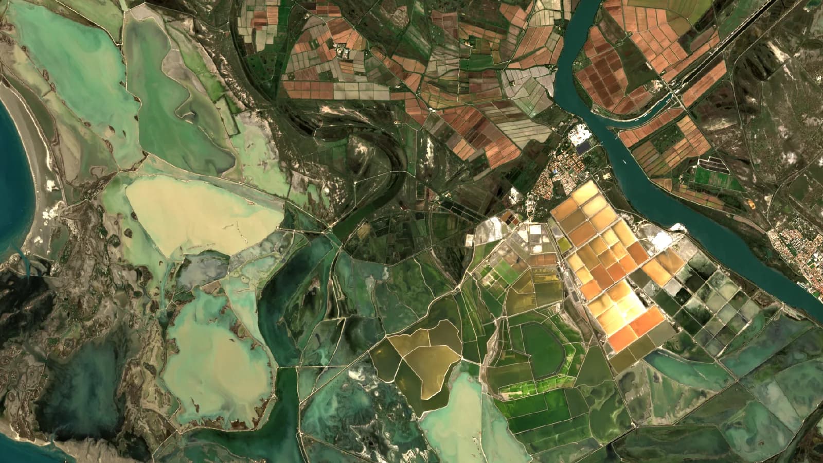 Immagine Sentinel-2 a colori reali del delta del Rodano, nel sud della Francia, con il fiume, le saline in arancione e crema, le lagune e i campi coltivati.