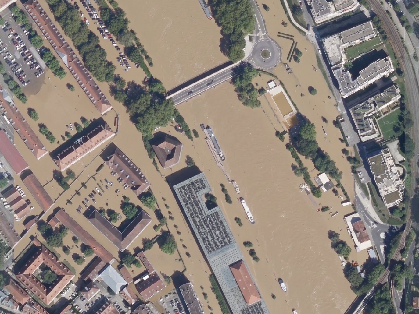 A flood covering the whole frame, then the same flood confined to the river corridor with the town on its terrace left dry (before)