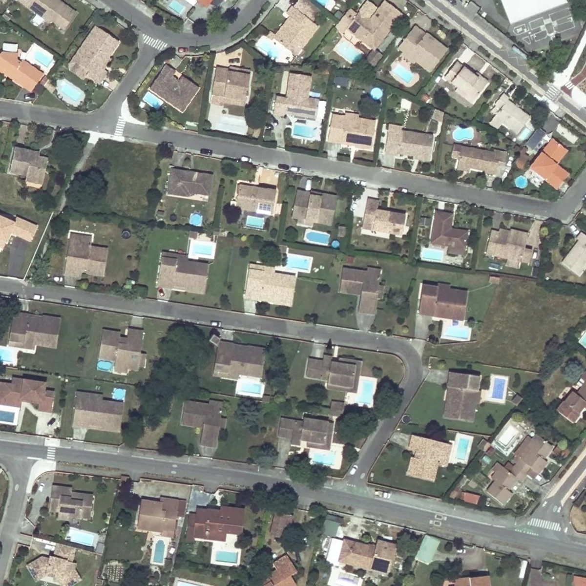 A residential block of Tournefeuille near Toulouse with houses, garden swimming pools, trees and curved streets at 20 cm, then the same square as a grid of 24 by 24 Sentinel-2 pixels in muted greens and greys where no house or pool can be picked out. (before)